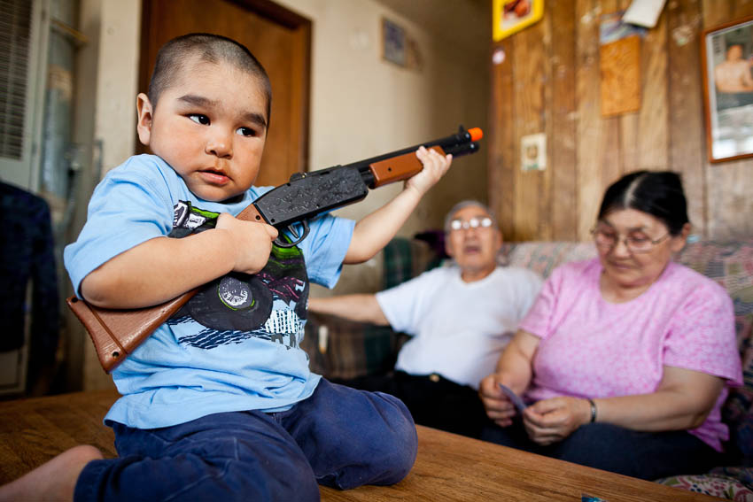 3 year old Shane Miles Akeya plays with his toy gun at home in Savoonga